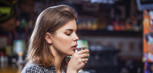 Drunk woman holding a glass of whisky or rum. Woman in depression. Young beautiful woman drinking...