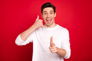 Photo portrait brunet in white shirt pointing at you showing call me sign isolated vivid red color...
