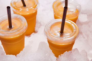 Cold mango smoothies over a pieces of ice. Refreshing beverage