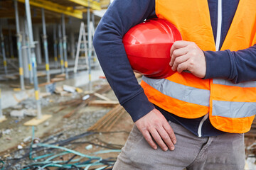 Arbeiter auf einer Baustelle mit rotem Schutzhelm
