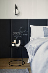 Stylish composition of small modern bedroom interior. Bed, creative lamp and elegant personal...