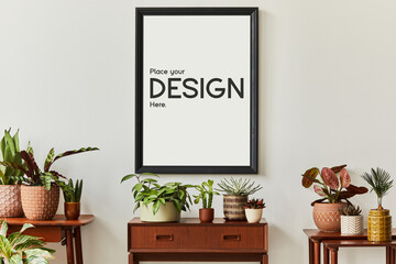 Creative composition of cozy plants lover home interior design with mock up poster frame, wooden furniture and different plants in designed pots. Home garden and nature love concepts. Template.