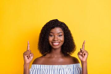 Portrait of attractive cheerful girl demonstrating up copy empty place space solution isolated over bright yellow color background