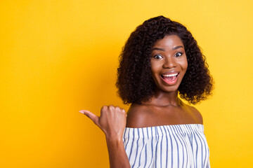 Photo of astonished dark skin girl open mouth direct thumb empty space isolated on yellow color background