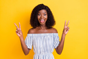 Portrait of attractive cheerful girl showing double v-sign having fun isolated over bright yellow...