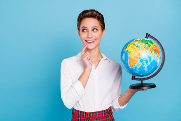 Photo of smart blond millennial lady hold globe look empty space wear shirt isolated on blue color background