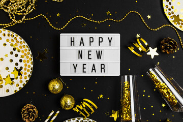 Happy new year 2022 with champagne glass ,party blower,tinsel,confetti, christmas balls. Fun Celebration holiday party time table on black background