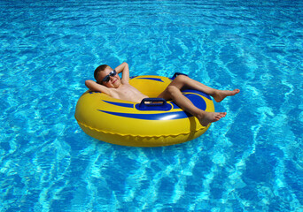 Boy relaxing on the inflatable ring in swimming pool.