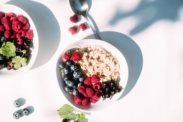 Oatmeal with raspberries and blueberries in a white plate .Breakfast