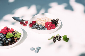 Oatmeal with raspberries and blueberries in a white plate .Breakfast