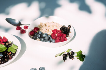 Oatmeal with raspberries and blueberries in a white plate .Breakfast
