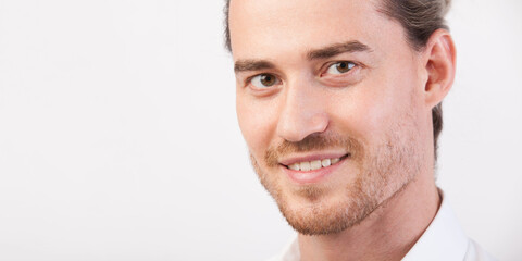 Close up young handsome manly man portrait with beard, happily smiling and looking in camera. Man posing in three quarters. Photo with copy space. Horizontal wide shot