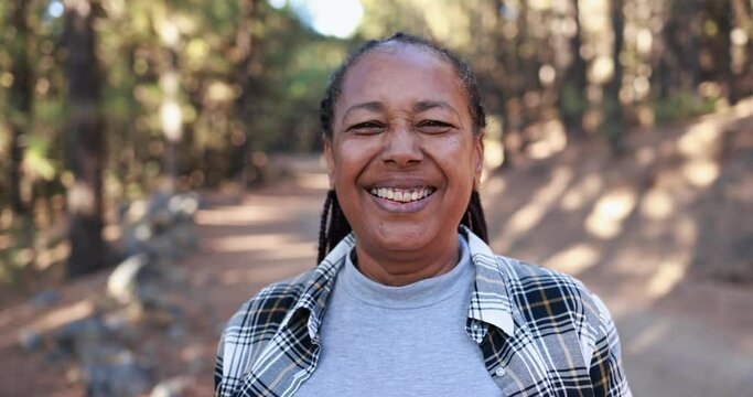 African senior woman smiling on camera with forest in background