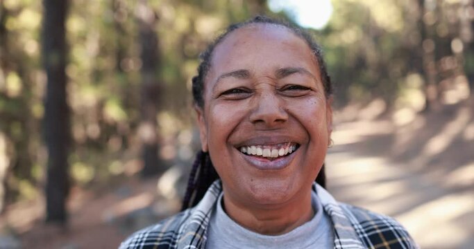 Mature african american woman smiling on camera with forest in the background