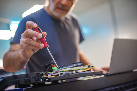 Field service maintenance engineer technician electrician inspect and control machine hardware and software system with laptop computer. Electric installation