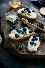 Bruschetta with cheese, blueberries and honey on a wooden background