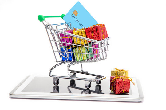  Two giftboxes and shoppingcart containing colorful gifts and credit card kept on a mobilephone.