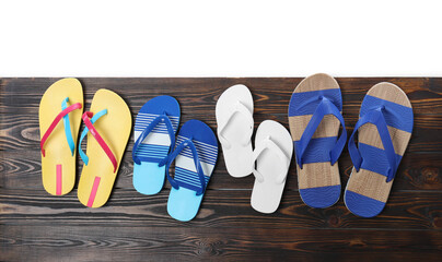 Different stylish flip flops on wooden table against white background, top view