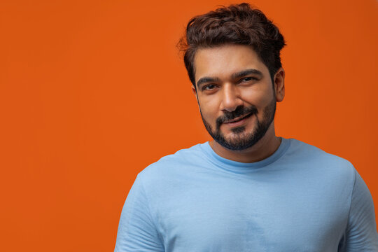 Portrait of a man smirking against plain backdrop.