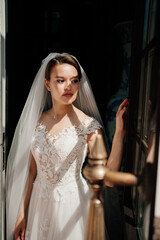 Fototapeta na wymiar a beautiful and gentle bride in a dark room by the window. 