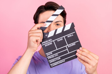 Portrait of attractive funny guy filmmaker using board closing face practicing isolated over pink...