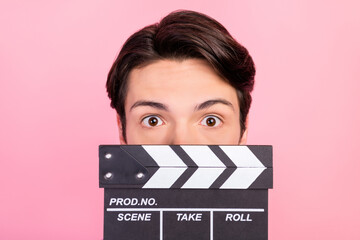 Portrait of attractive funny guy filmmaker closing face with chalkboard isolated over pink pastel...