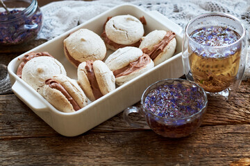 Almond cookies with chocolate cream. Cornflower blue tea, wood background, side view.
