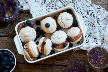 Almond cookies with chocolate cream. Blueberries, cornflower blue tea, wood background, top view.