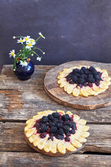 blackberry flower pie on a wooden table. Flowers, coffee, shortcrust pastry, ricotta, ice cream, chamomile, side view.
