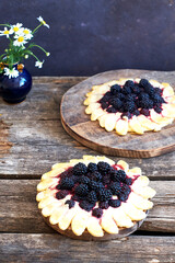 blackberry flower pie on a wooden table. Flowers, coffee, shortcrust pastry, ricotta, ice cream, chamomile, side view.