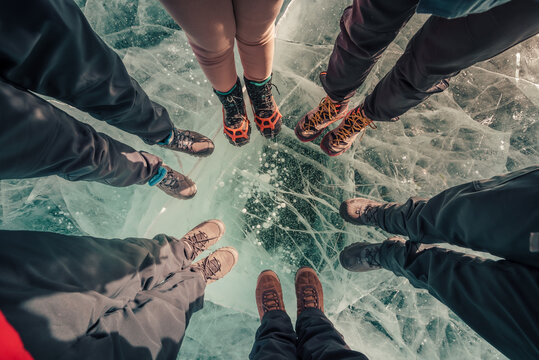 Traveller foot standing on natural breaking ice in frozen water at Lake Baikal, Siberia, Russia.