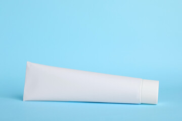 Blank tube of toothpaste on light blue background. Space for text