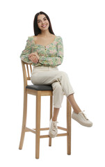 Beautiful young woman sitting on stool against white background