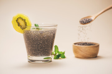 Selective focus of chia seeds drink with water in transparent glass with slice of kiwi