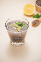 Selective focus of chia seeds drink with water in transparent glass with lemon balm.