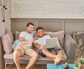 Two men friends shopping online via laptop, credit card at the room, buying from home.