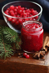 Cranberry sauce in a flas jar on rustic background, traditional holiday berry jam for christmas or thanksgiving, closeup, copy space, healthy homemade canned food concept