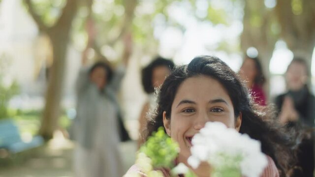 Front view of happy girl catching bridal bouquet. Pretty curly-haired woman at wedding of her lesbian friends in summer park. LGBT wedding, tradition concept
