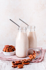 Pecan milk in glass bottles with reusable metal drinking straw