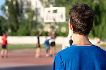 Fototapeta premium A teenage guy stands at the stadium and looks at basketball