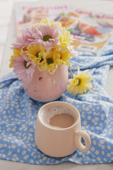Cup of fresh coffee and beautiful bouquet on light blue printed cloth. Good morning