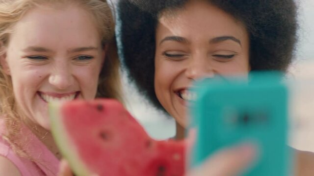 two beautiful women posing with watermelon taking photos using smartphone woman kissing friend on cheek happy girl friends sharing relationship on social media having fun on seaside 4k