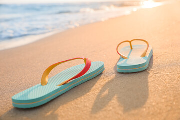 Bright turquoise beach slippers on sand near sea