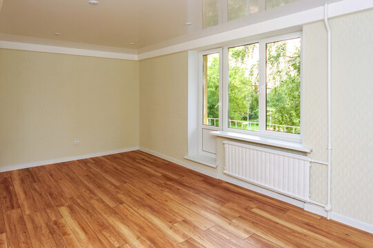 Empty bright room with a wooden floor and light wallpaper. The apartment is after renovation.