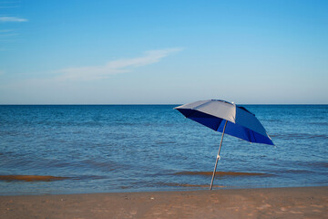 lonely beach umbrella on the seashore on a sunny day against the backdrop of the sea.