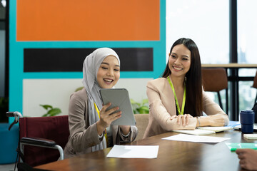 Asian Muslim woman in hijab headscarf sitting on wheelchair presenting of her work to corporate...