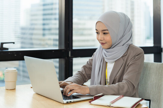 Asian Muslim business woman in hijab headscarf working with computer laptop in the modern office. business people, diversity and office concept