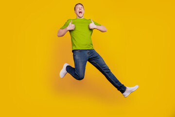 Fototapeta na wymiar Full length photo of nice attractive cheerful optimistic guy show thum-up like cool jump up isolated over yellow background