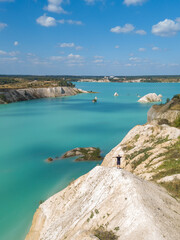 Drone view of a man standing on a mountain against the background of blue chalk quarries with his hands raised up in the summer. Concept of freedom