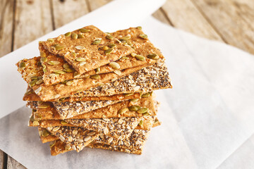 Crunchy crispbread on recycled paper on wooden table. Whole Grain crisp bread with pumpkin,...